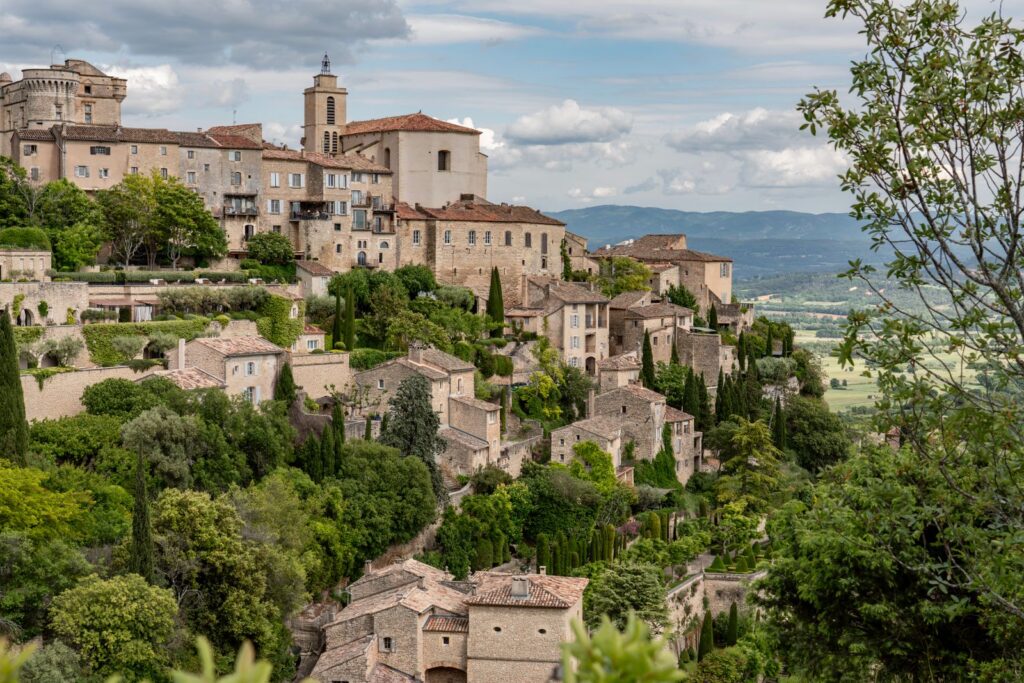 Le village perché de Gordes et ses maisons en pierre, entourés de verdure.